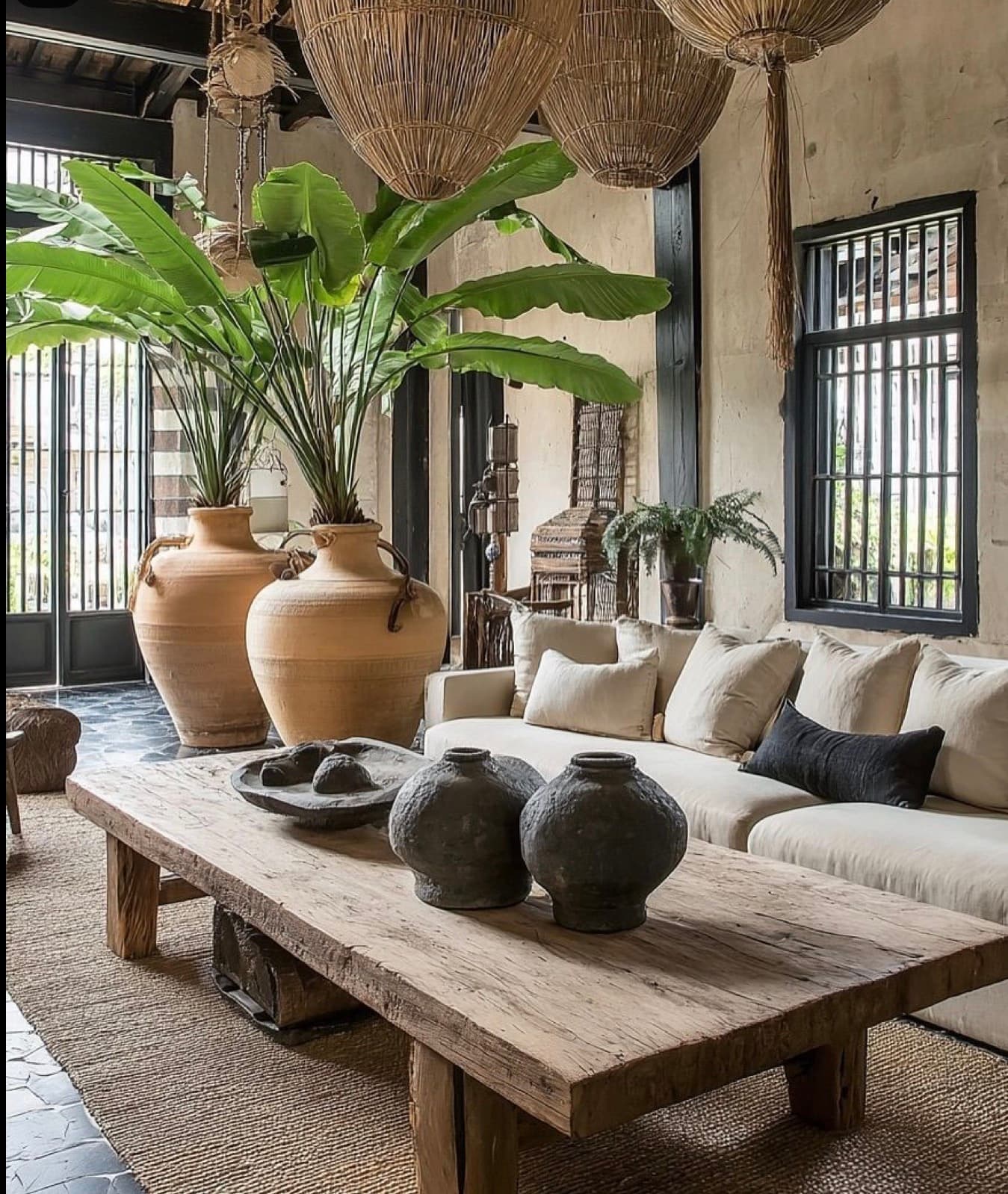 Rustic living room with large terracotta planters, a wooden coffee table, and woven basket lights.