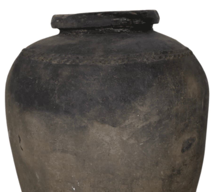 Weathered dark grey ceramic jar with a rounded body, narrow neck, and decorative shoulder band.